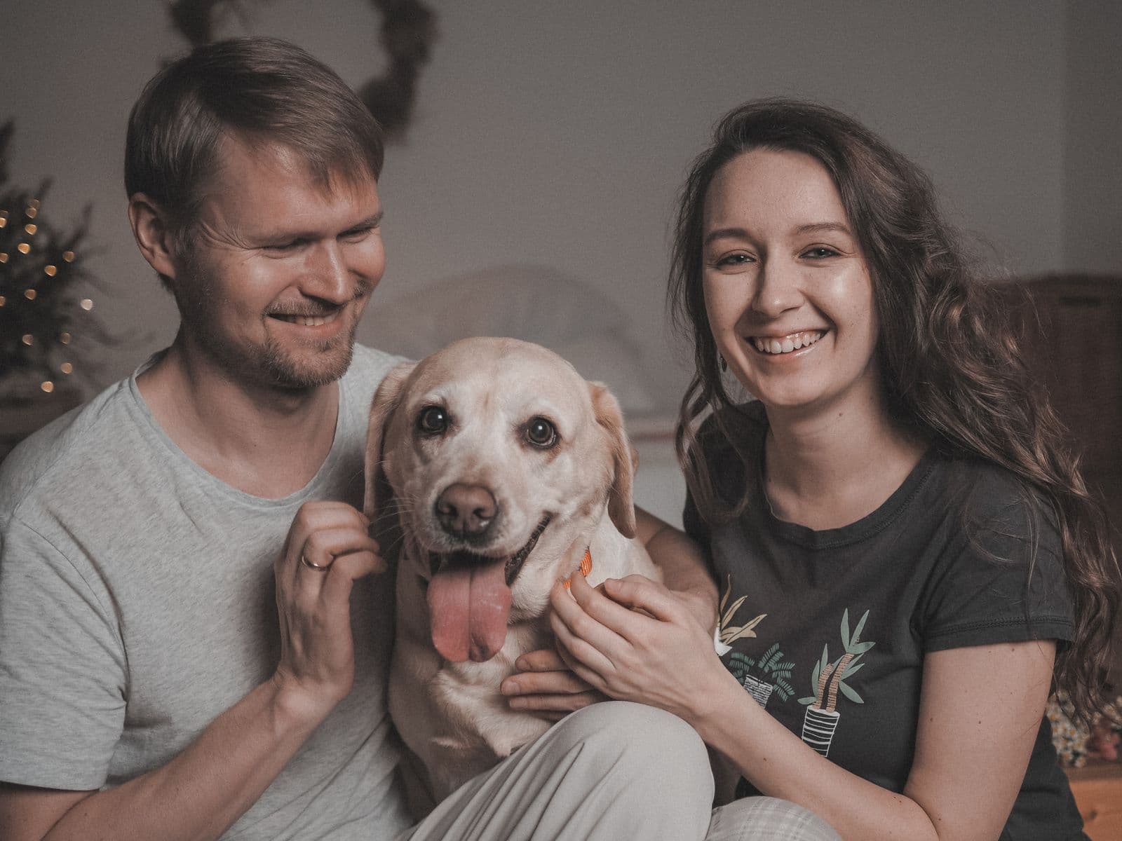 Couple jouant avec son chien dans le salon, illustrant l'assurance santé d'un animal de compagnie